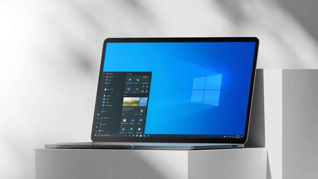 Laptop on a white pillar open to Windows 10 home screen.
