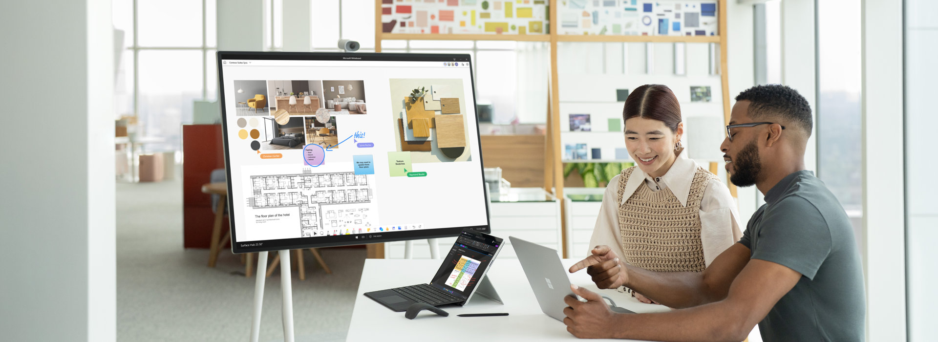 Two co-workers interact with two Surface Laptop 5 devices with a Hub 2S in the background